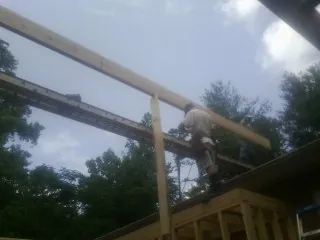 Carpenter setting a ridge beam over a new addition frame — Ice Dam Removal by Roofing Brothers in Fayville