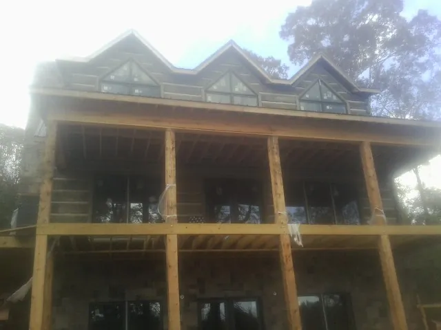 Dormers and porch framing on a large log home under construction — Roof Coating work by our crew in Fayville