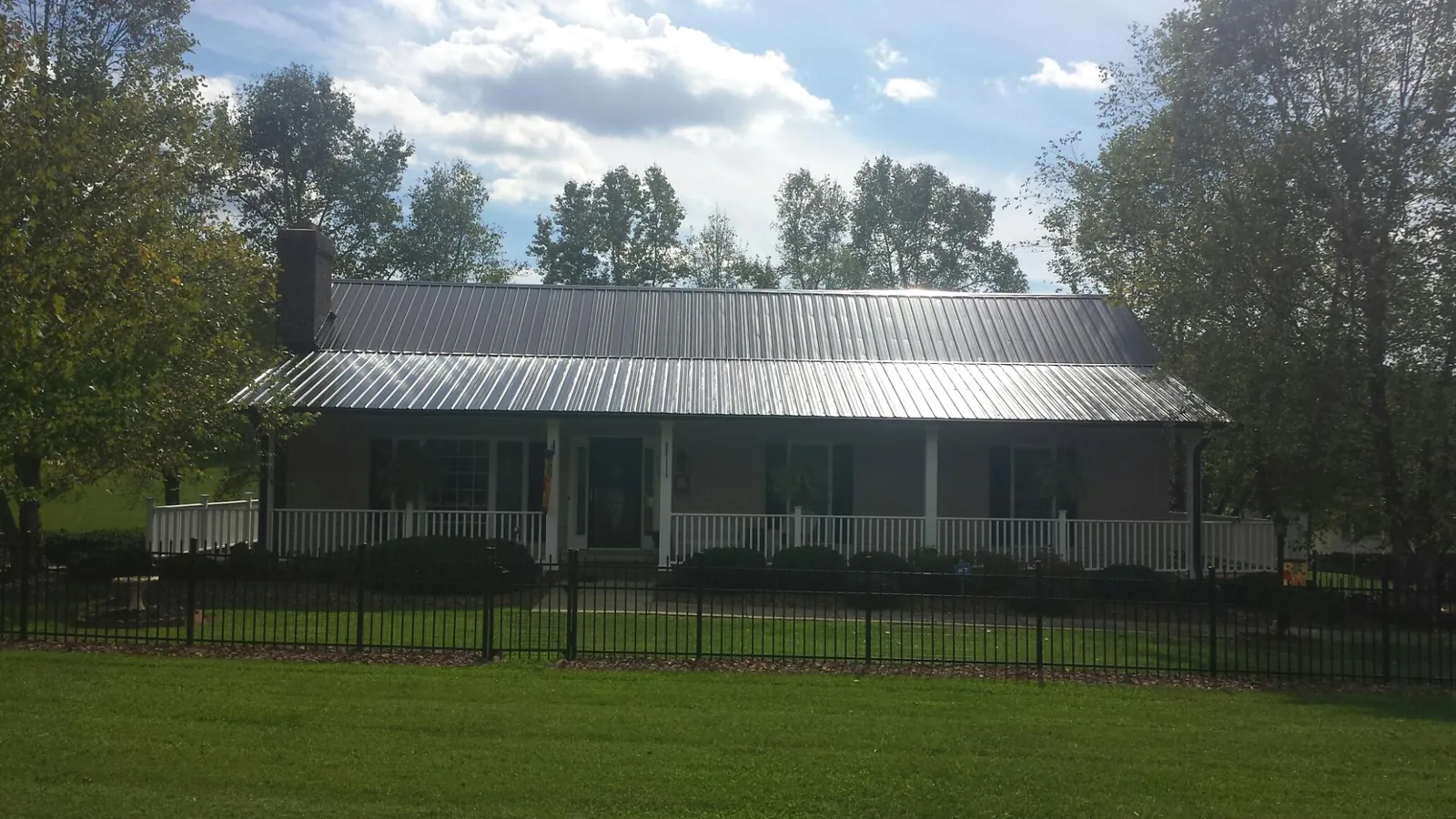 Gray metal roof on a brick ranch with a full width front porch — Gutter Guard Installation work by our crew in Fayville