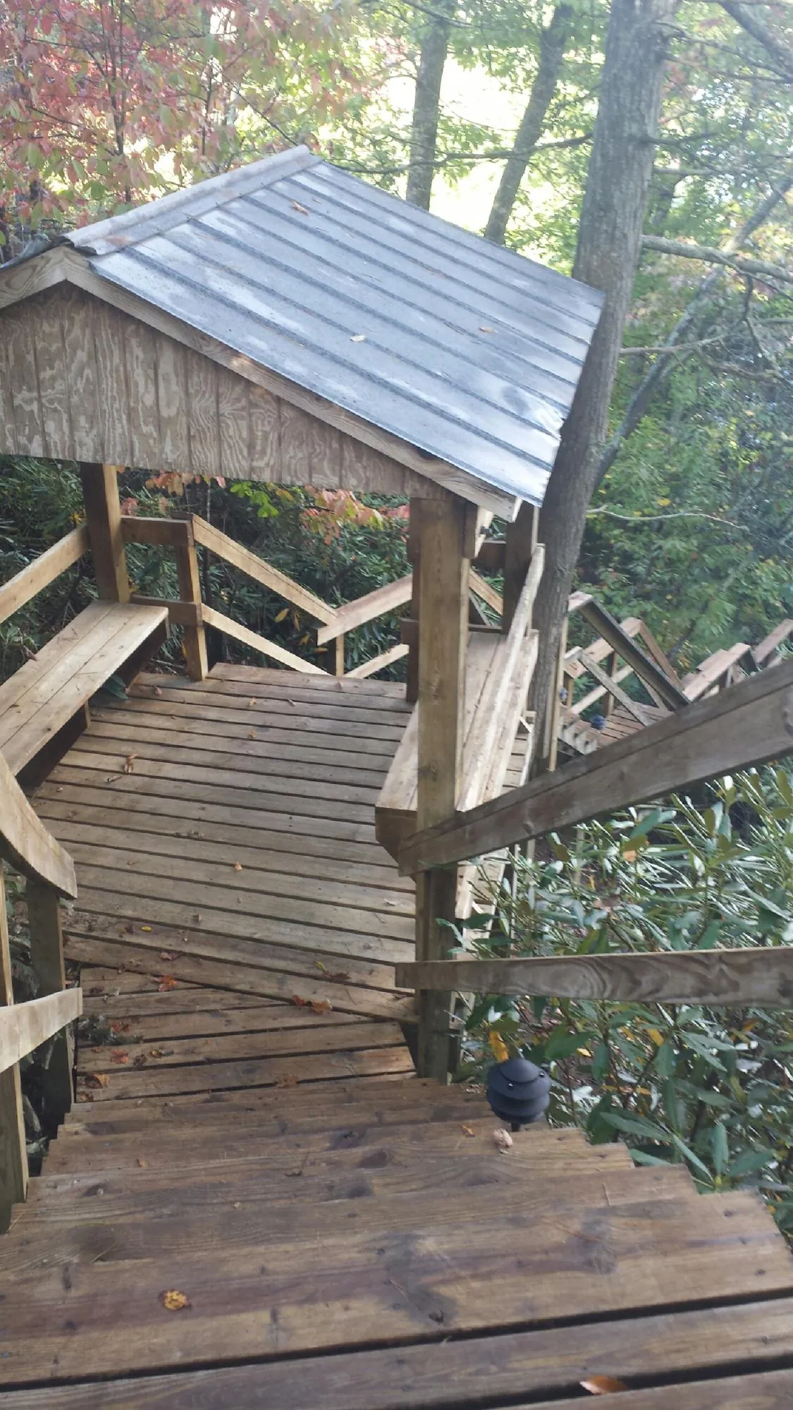 Metal roofed shelter over wooden steps on a wooded walkway — Skylight Repair & Installation work by our crew in Fayville