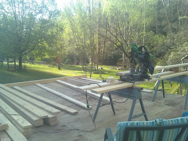 Miter saw and framing lumber on a deck under construction in Fayville