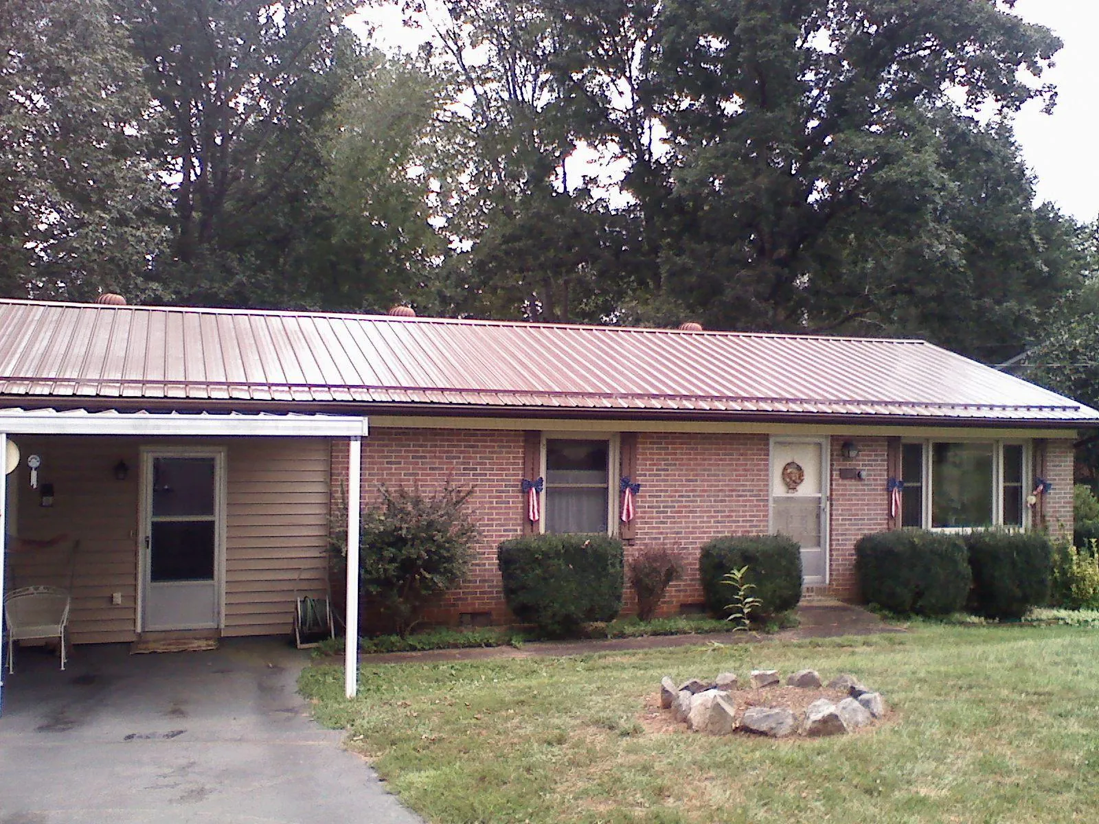 Bronze metal roof and carport on a brick ranch home — Roof Repair work by our crew in Fayville