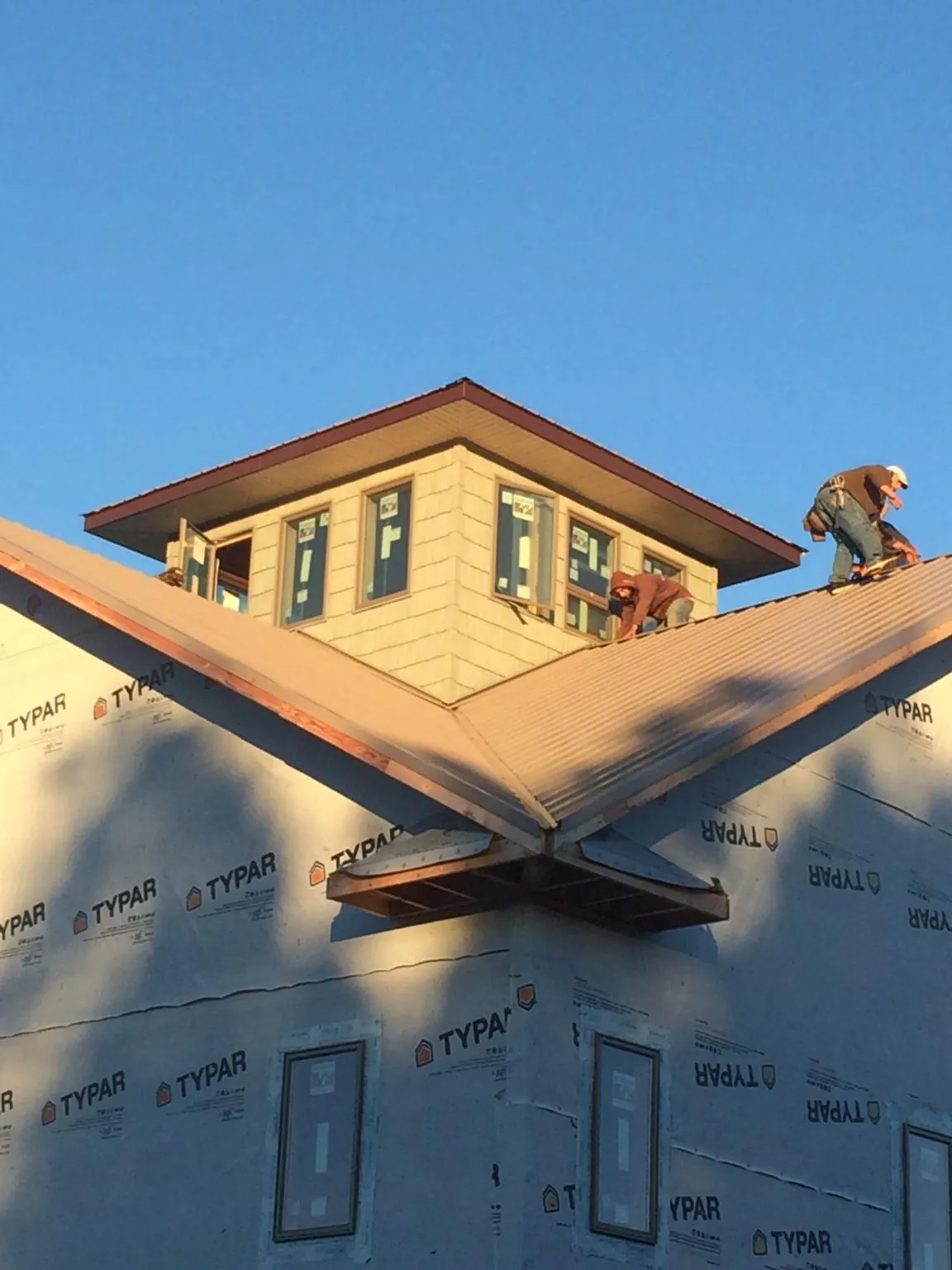 Roofers working around a rooftop cupola on a new metal roof at sunset — Roof Waterproofing in Fayville by Roofing Brothers